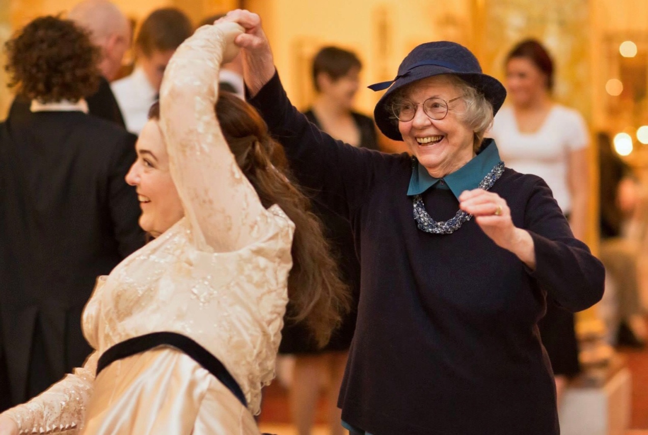 A photograph from my wedding in which my grandmother and I are dancing. She is twirling me. Both of us are smiling.